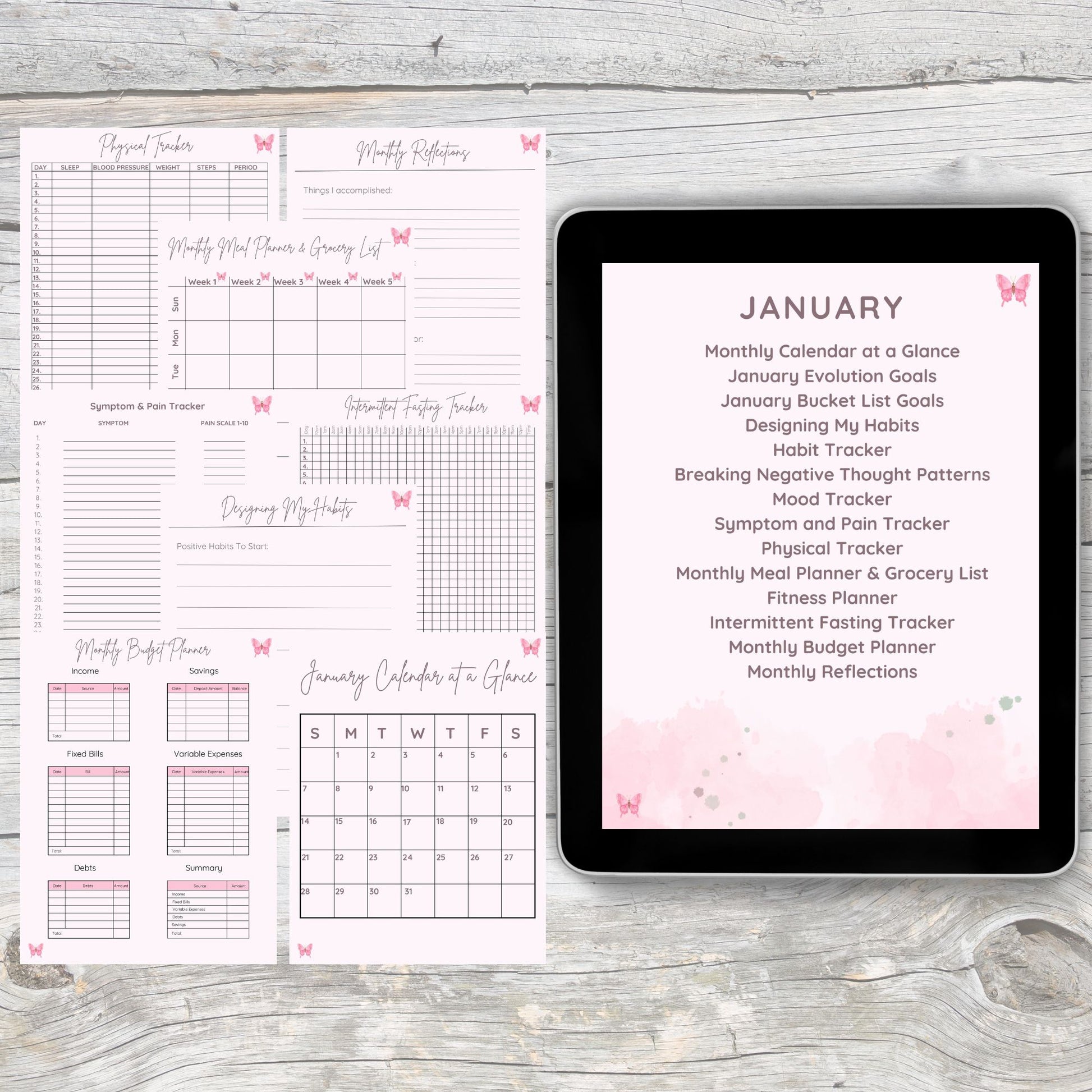 Black tablet laying on grey and white wooden desk.  Tablet displays pink digital monthly tracker pages.  Detailed pages lay on the desk left of the tablet.