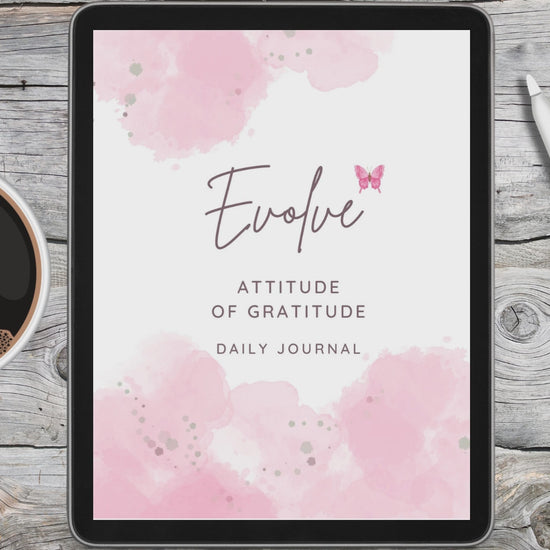 black tablet displaying pink and white digital gratitude journal on grey and white desk in between a white stylus pen and a cup of coffee