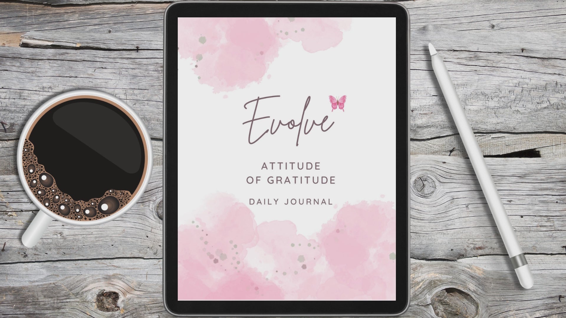 black tablet displaying pink and white digital gratitude journal on grey and white desk in between a white stylus pen and a cup of coffee